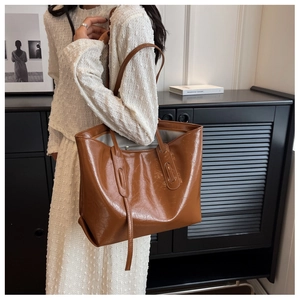 Detail of a brown tote bag with vintage cracked texture and glossy finish