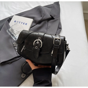 Detail of a black leather saddle bag with large silver buckle and adjustable strap