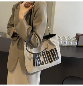 Detail of off-white canvas tote with MCAORI lettering and leather chain strap