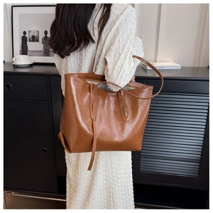 Detail shot of the glossy cracked leather texture on a brown shoulder tote bag