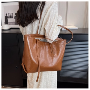 Brown large capacity tote bag with glossy crackle texture shown on shoulder