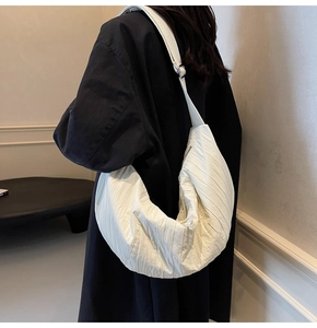 Dettaglio della borsa dumpling plissettata bianca con grande capacità e trama morbida