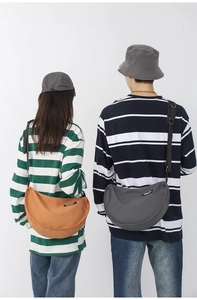 Rear view of models wearing large nylon crescent crossbody bags in orange and dark grey