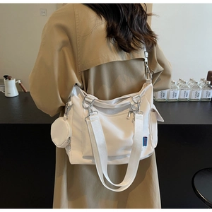 Detailed side view of white canvas tote bag with long straps and mini coin purse attachment