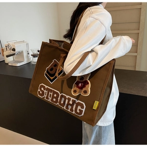 Brown canvas tote bag detail featuring vintage teddy bear embroidery and towel textures