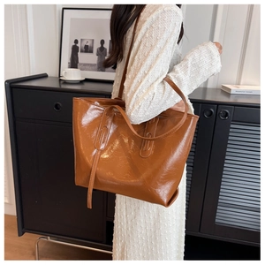 Close-up of a large capacity glossy brown tote bag with retro pleated texture on shoulder
