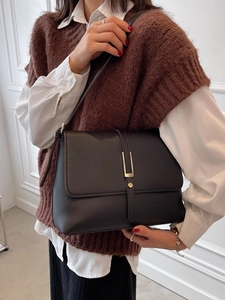 Minimalistische schwarze Umhängetasche aus Leder mit goldener Hardware am Modell