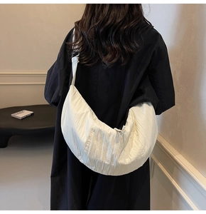 Dettaglio della borsa a mezzaluna in nylon crema con tessuto pieghettato e tracolla