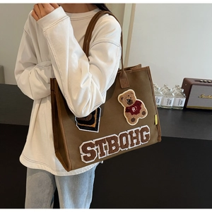 Detailed plush bear embroidery and STBQHG letters on a brown canvas tote bag