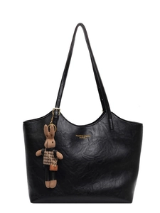 Black leather tote bag with rabbit charm and gold fashion lettering on white background