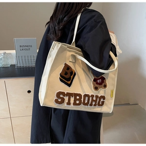 Detail of chenille embroidery patches with bear and letters on cream canvas tote bag