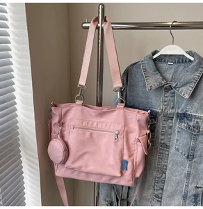 Pink canvas tote bag detail featuring front zipper pocket and round coin purse attachment