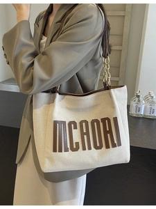 Chic canvas tote bag with brown leather trim and chain strap for autumn commute