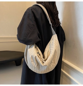Dettaglio della borsa a tracolla in nylon beige plissettato con trama e zip argentata