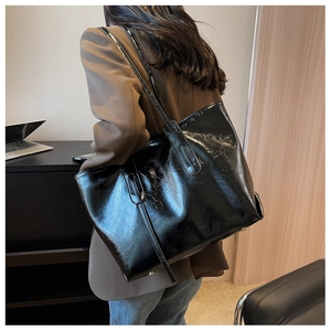 Detail of the large black tote bag with glossy crinkled leather texture and long straps