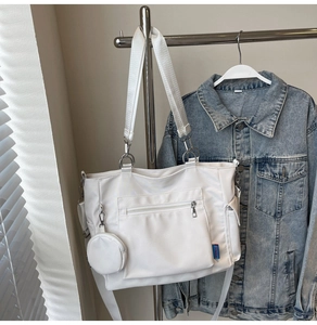 Macro view of white nylon tote bag with multi-pocket design and round coin purse charm