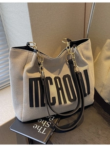 Chic beige woven tote bag with black leather trim and chain strap for autumn style