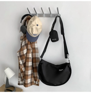 Detail of black nylon crescent bag on hook with mini pouch and adjustable strap