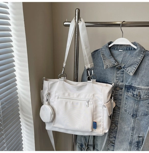 Close-up of white canvas tote bag with multi-pockets, broad strap and a small coin purse