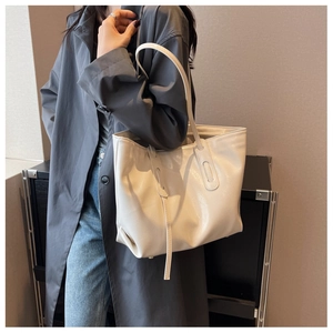 Side view of a large cream tote bag with glossy wrinkled texture on a female model