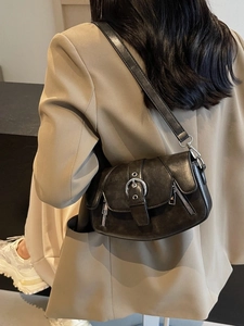 Vintage black saddle bag with silver buckle and zippers shown from a side view