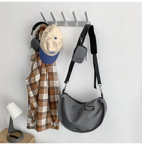 Detail of dark grey nylon crescent crossbody bag with mini pouch in daily setup
