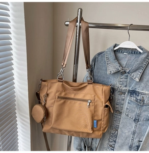 Detailed side view of khaki nylon tote bag featuring side pocket and mini coin purse charm