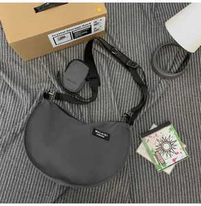 Detail of dark grey nylon crescent bag with adjustable strap and mini round coin pouch
