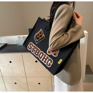 Detail of black canvas tote bag with plush embroidery patches and sturdy shoulder straps