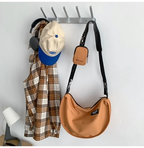Brown nylon crescent bag with adjustable strap and small pouch on white wall
