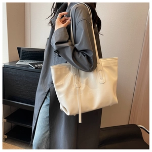 Detail of creamy white tote bag with glossy wrinkled texture and reinforced straps