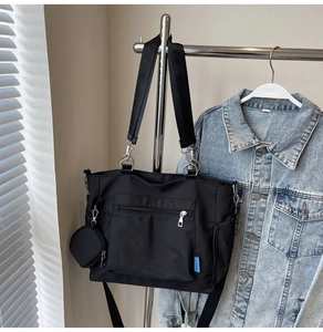 Detailed view of black nylon tote bag with multiple zipper pockets and mini coin purse