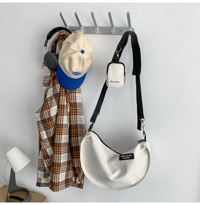 Close-up of white nylon half-moon crossbody bag with adjustable strap and small pouch