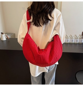 Dettaglio della borsa a mezzaluna in nylon rosso plissettato con ampia tracolla