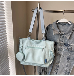 Detail of mint green nylon tote bag featuring front zip pocket and small round coin purse