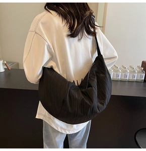 Dettaglio borsa a mezzaluna in nylon nero con design a pieghe e ampia tracolla morbida