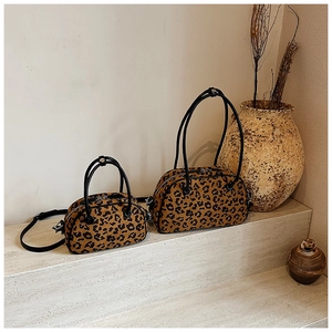 Detail von Boston-Taschen mit Leopardenmuster und schwarzen Ledergriffen auf Steinstufen