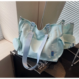 Close-up of light blue nylon tote bag with detachable wide strap and small round pouch