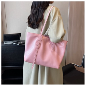 Detail of pink glossy tote bag showing textured leather material and rivet feet