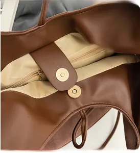 Close-up of brown suede tote bag with magnetic gold snap closure and internal zipper pocket