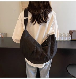 Dettaglio della borsa a mezzaluna in nylon nero plissettato con tracolla larga
