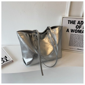 Detailed view of silver tote bag with metallic crinkled texture on minimalist display