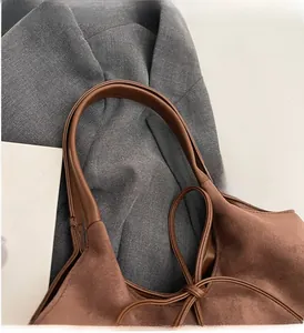 Close-up of brown suede tote bag handles with premium leather texture and stitching