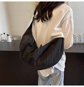 Dettaglio di una borsa a tracolla in nylon nero plissettato con design capiente