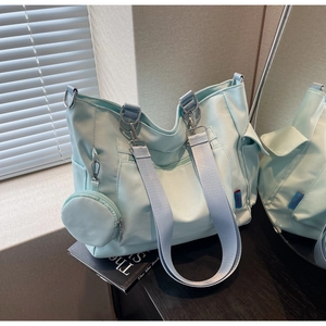 Detail of mint green canvas tote with multi-pocket design and detachable small pouch