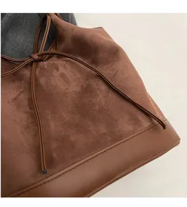Detail of dark brown suede tote bag featuring elegant leather bow and soft texture
