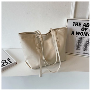 Detail of minimalist cream-colored large tote bag with fine texture and slim straps