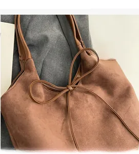 Detail view of brown matte suede tote bag with elegant bow leather drawstring accent
