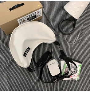 Detailed view of white nylon crescent bag with adjustable black strap and mini pouch