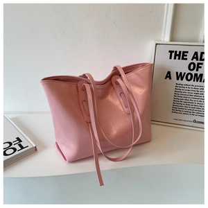 Detail of a pink tote bag showing glossy waxed leather texture and slim shoulder straps